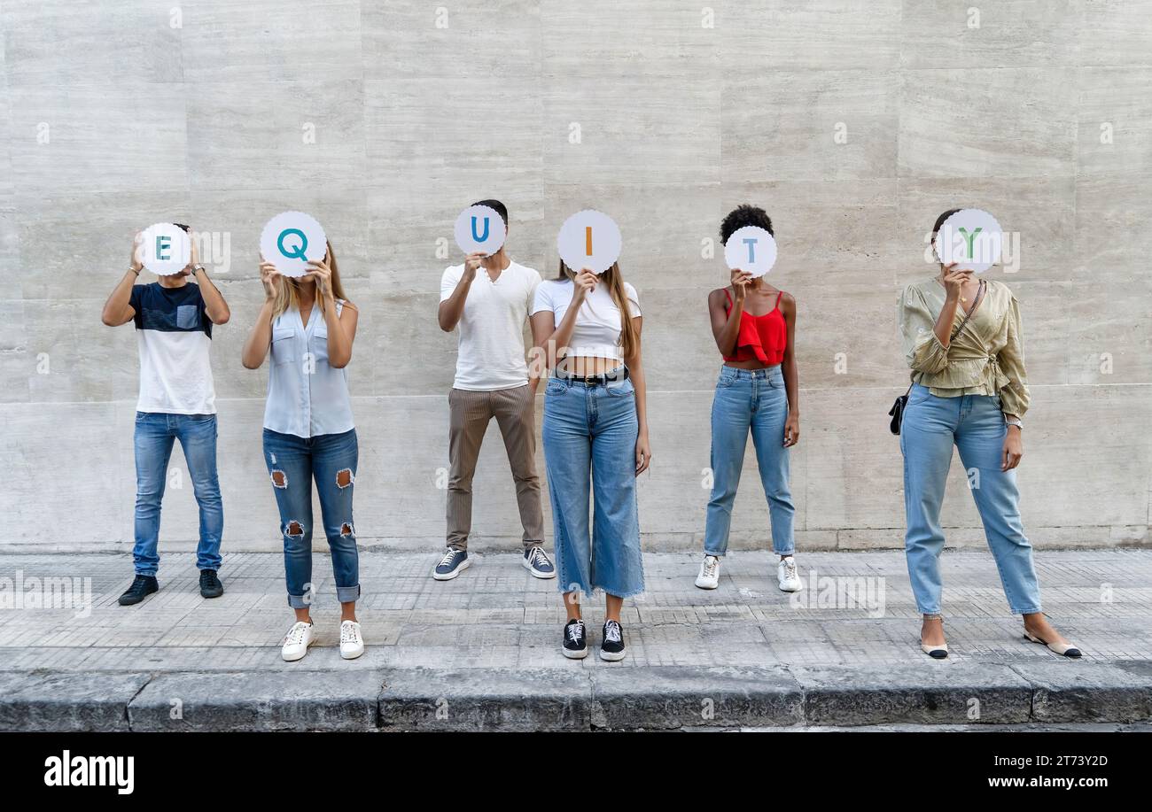 Eine vielfältige Gruppe junger Erwachsener, die die Buchstaben "GLEICHHEIT" hochhalten und damit ihre Unterstützung für Gleichheit und Inklusion in der Gesellschaft symbolisieren. Stockfoto