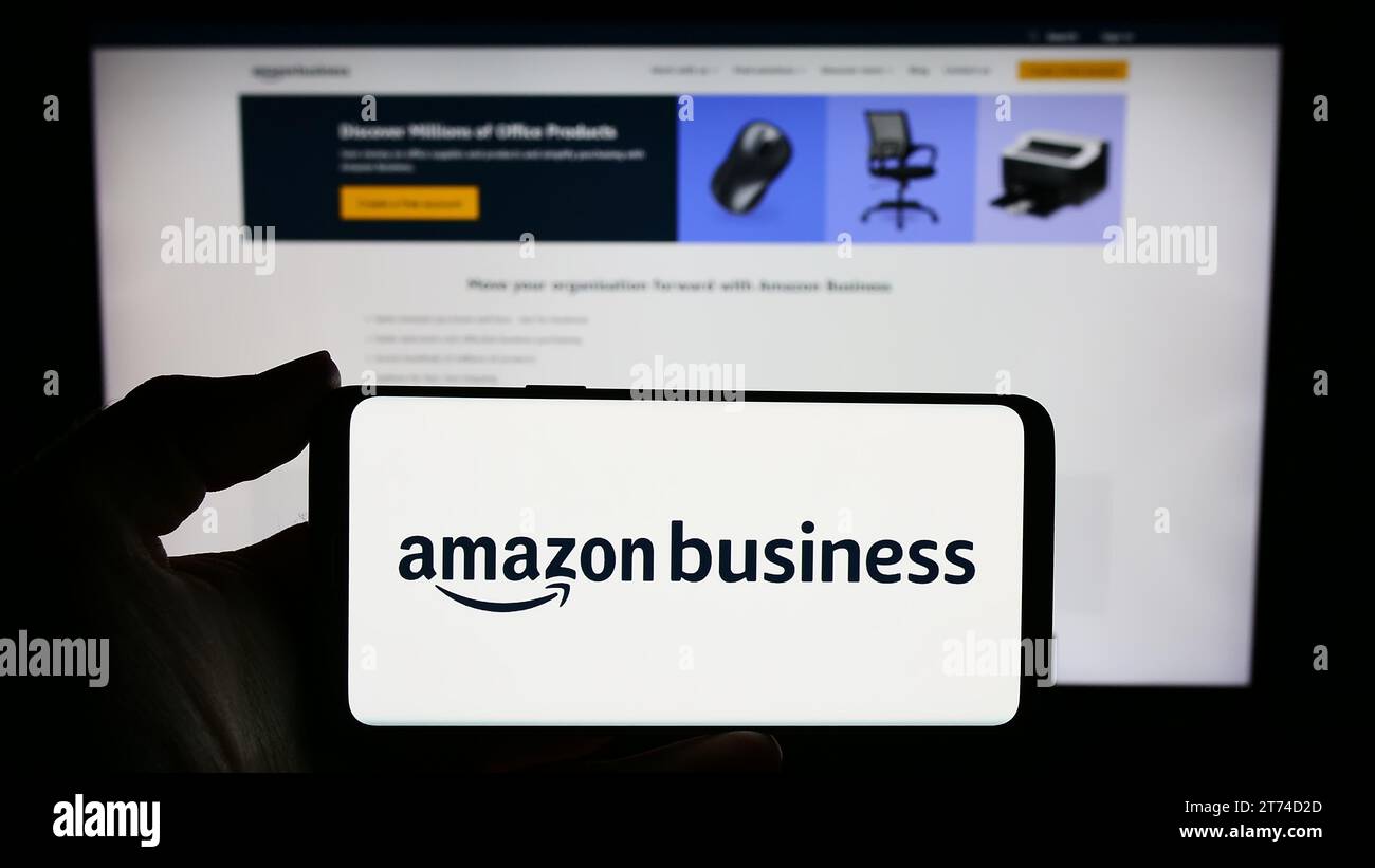 Person, die ein Smartphone mit dem Logo des US-amerikanischen Unternehmens Amazon Business für E-Commerce-Plattformen hält, vor der Website. Schwerpunkt auf dem Display des Telefons. Stockfoto