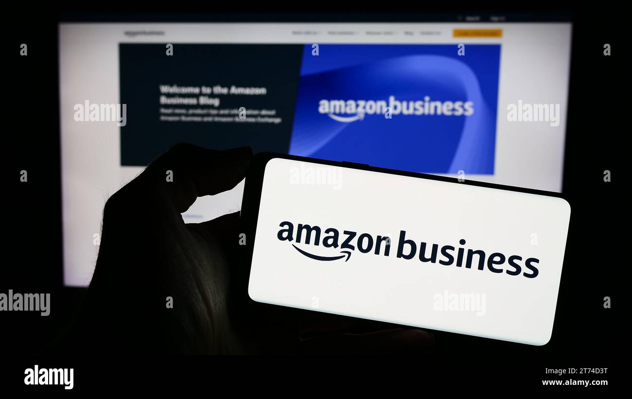 Person, die ein Mobiltelefon mit dem Logo des US-Unternehmens Amazon Business für E-Commerce-Plattformen hält, vor der Business-Webseite. Schwerpunkt auf dem Display des Telefons. Stockfoto