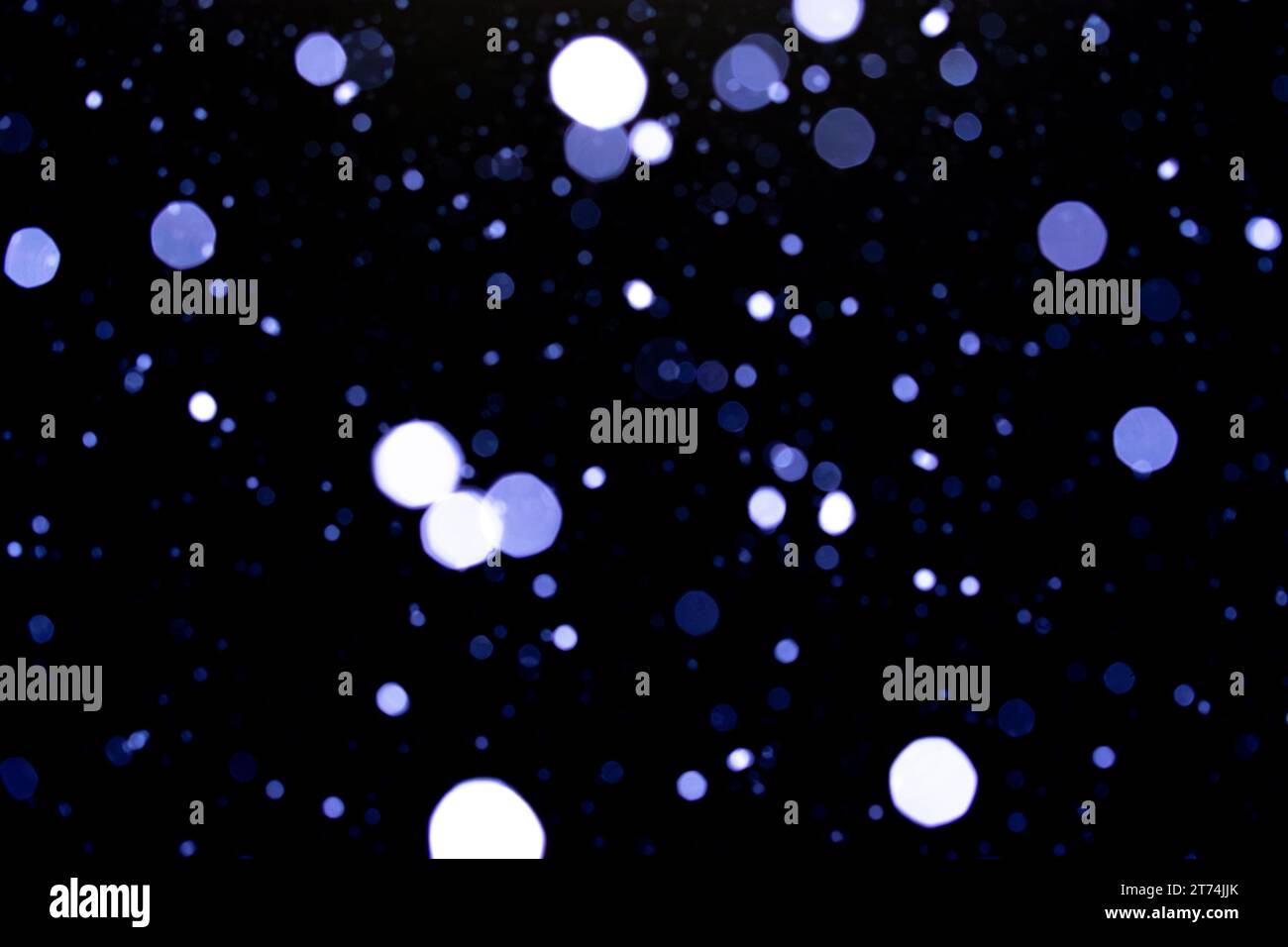 Abstraktes Foto von Schneeflocken, die nachts fallen, Kreise unterschiedlicher Größe und Farben, die sich wie ein winterliches Sternenfeld in die Ferne erstrecken. Stockfoto