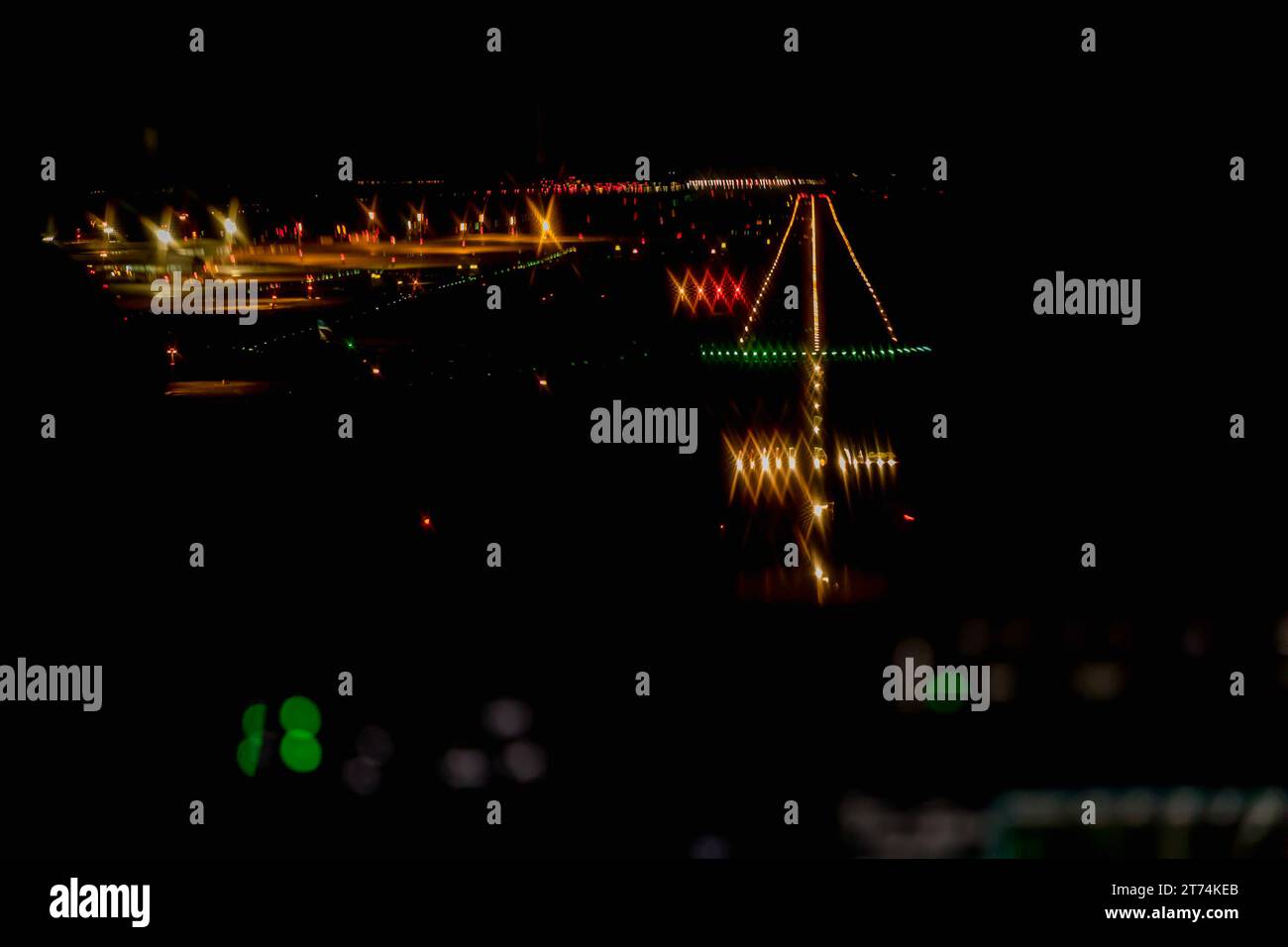 Blick aus dem Cockpit eines modernen Flugzeugs, das nachts auf einem beleuchteten Flughafen landet. Beleuchtetes Cockpit-Armaturenbrett aus Glas bei der Landung am Flughafen Stockfoto