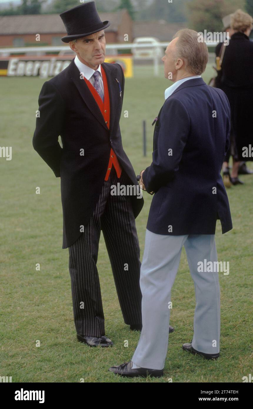 Kontrastierender Stil und soziale Klasse zwei Männer Freunde der 1980er Jahre England. Derby Day Pferderennen, ein Mann informell und elegant gekleidet, ein anderer Mann formell mit schwarzem Seidenoberteil und Schwanzmantel. Epsom Downs, Surrey England UK 1985 HOMER SYKES Stockfoto