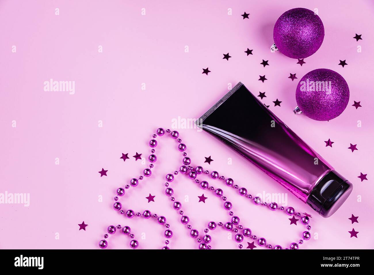 Stilvolle Plastikflasche Kosmetik auf rosa Hintergrund. Drücken Sie die Tube Hautpflegecreme oder -Lotion und die Weihnachtsdekoration zusammen. Produkt ohne Marke für Adv Stockfoto
