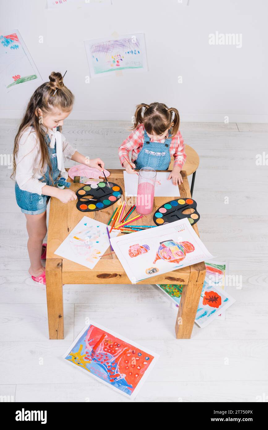 Zwei kleine Mädchen, die mit einem Aquarellpapiertisch malen Stockfoto