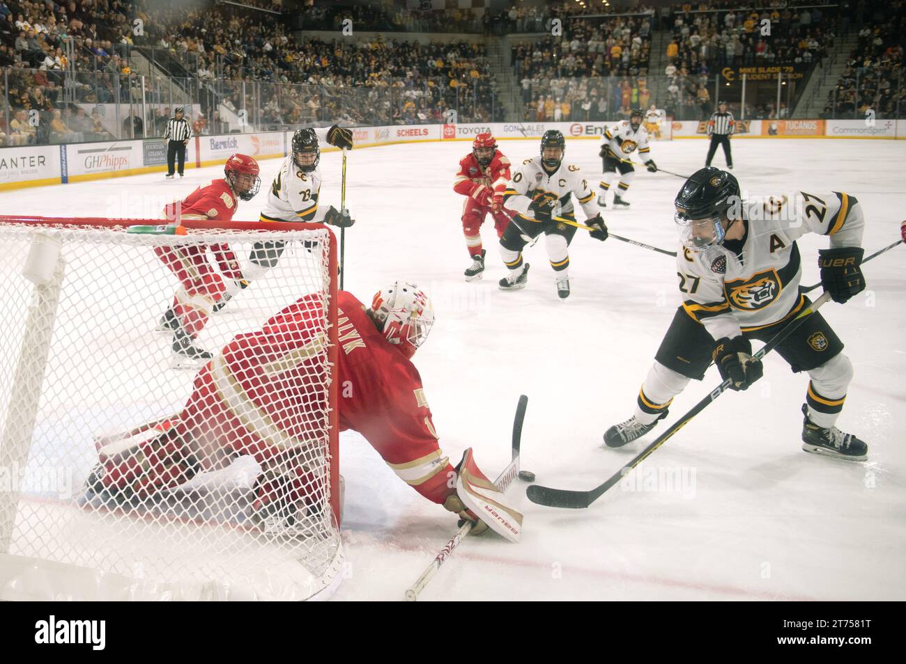 Stanley Cooley vom Colorado College (weiße #27) versucht, in einem College-Hockeyspiel in der Robson Arena gegen den Torwart der Denver University zu schießen. Stockfoto