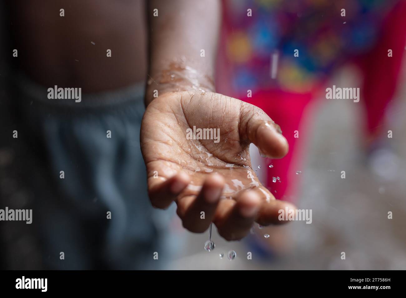 Wassertropfen fallen während eines Monsunregen auf die Handfläche eines Jungen, in der Gegend von Tejgaon Slum, Dhaka, Bangladesch Stockfoto