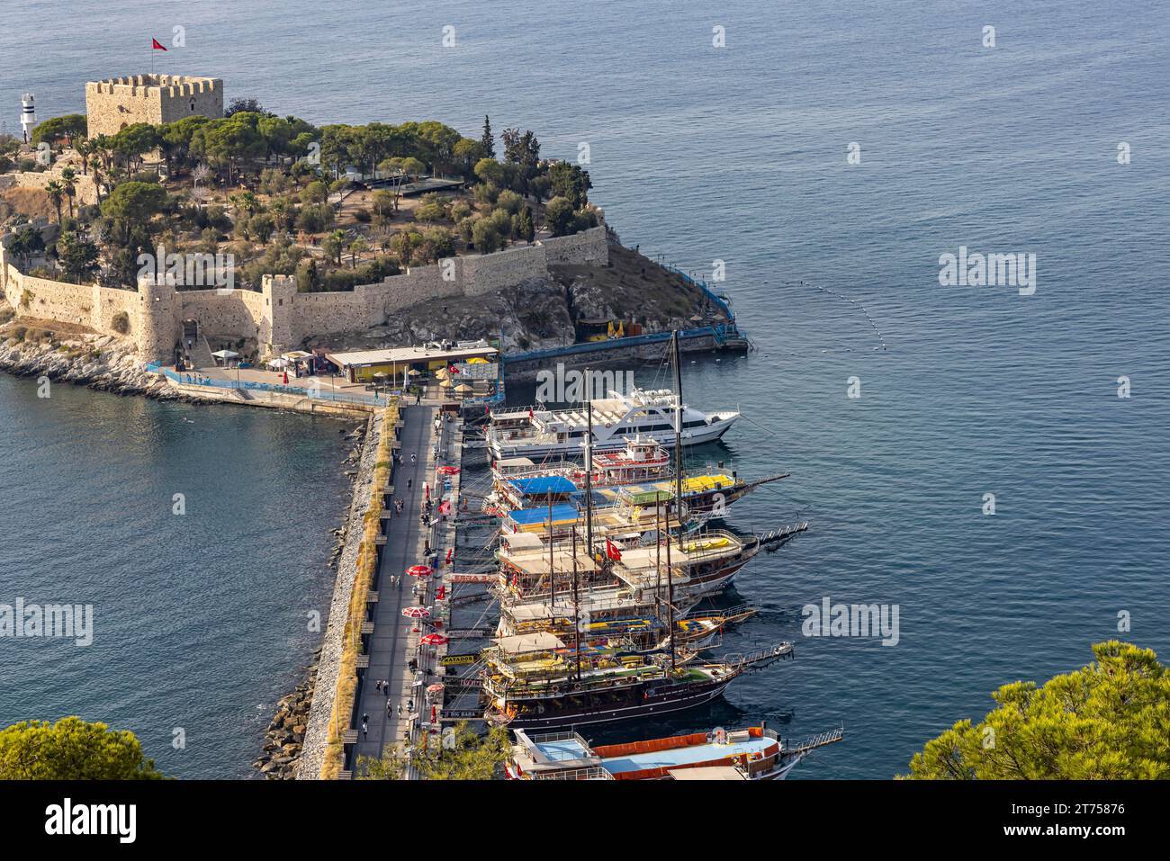 Ausflugsboote liegen am Damm zur Pigeon Island in der Bucht von Kusadasi. Auf dem Gipfel der Insel Kusadasi erhebt sich eine genuesische Festung Stockfoto
