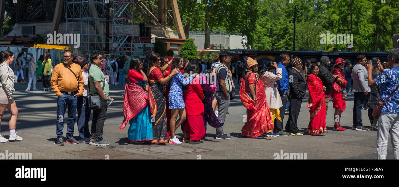 Touristen mit bunten Gewändern warten vor dem Eingang zum Eiffelturm, Paris, Frankreich Stockfoto