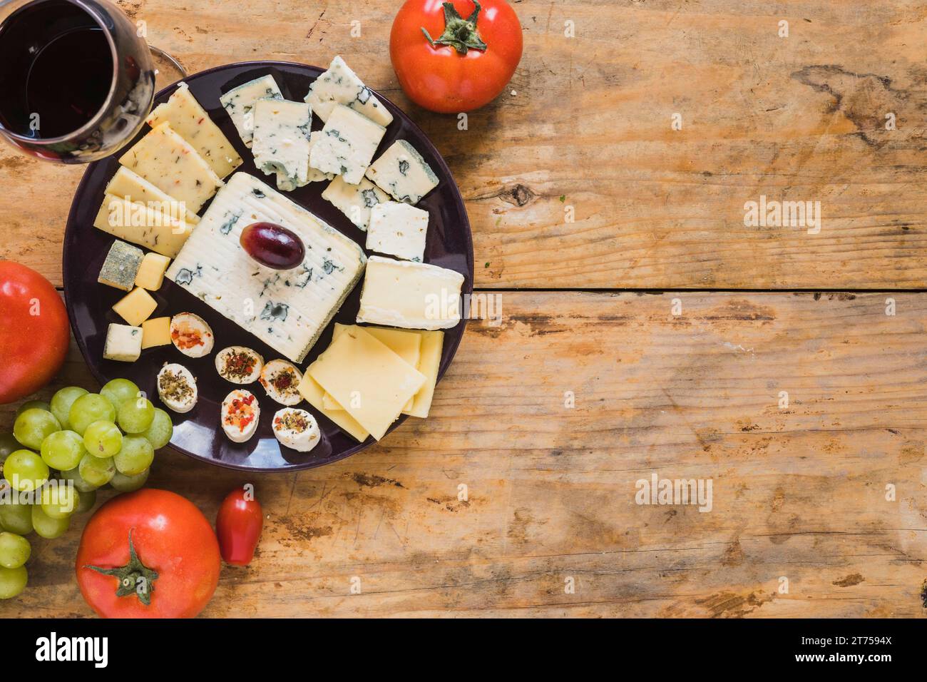 Käseplatte mit Tomaten, Trauben, Holztisch Stockfoto