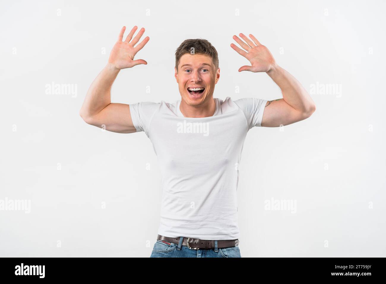 Der aufgeregte junge Mann, der ihre Arme hebt, gibt High Five vor weißem Hintergrund Stockfoto