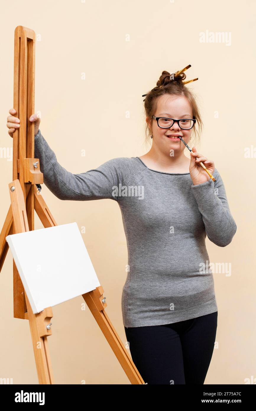 Glückliches Mädchen mit Down-Syndrom posiert Staffelei Stockfoto