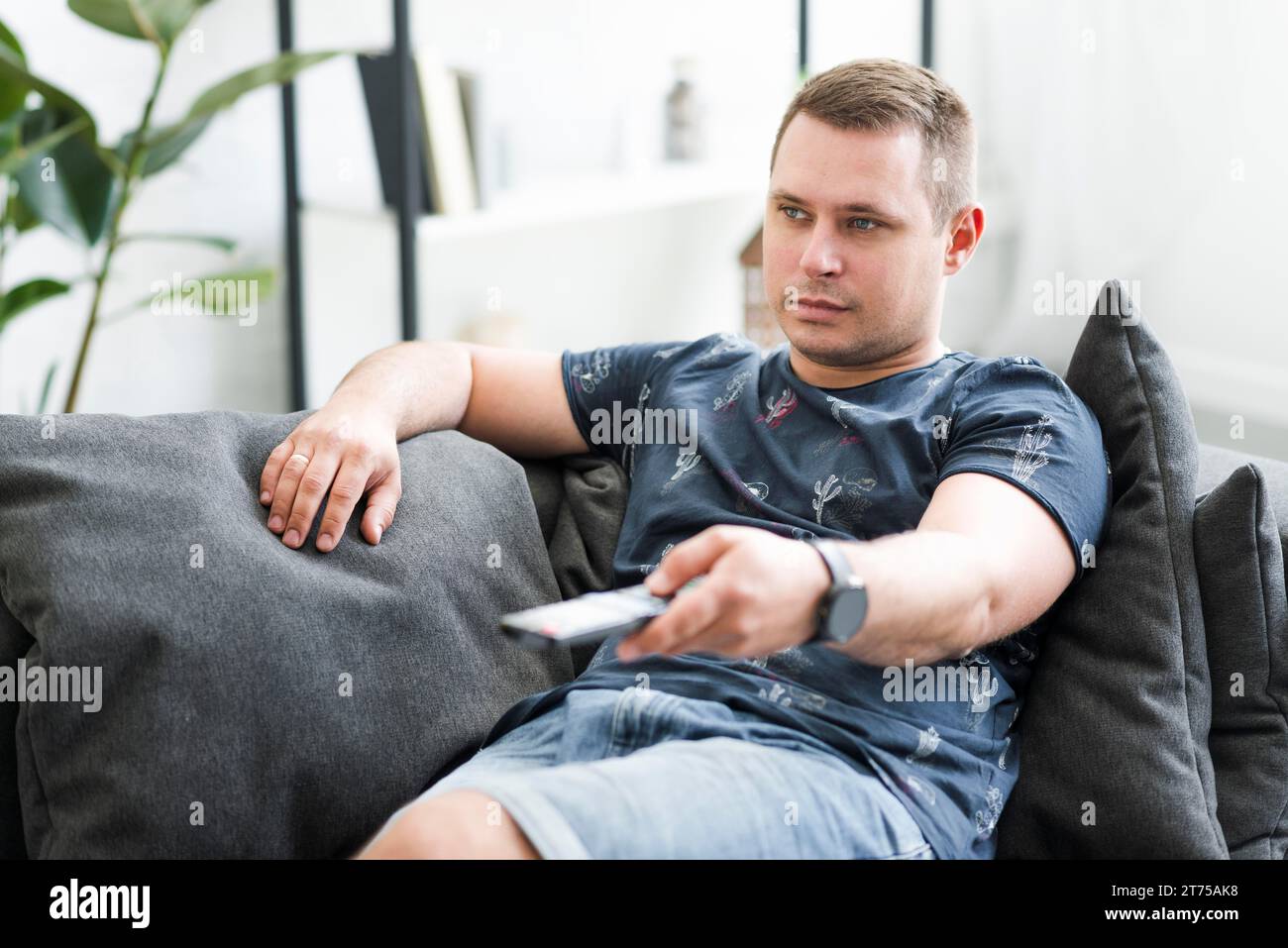 Mann im mittleren Erwachsenenalter, der auf Sofa sitzt und fernsehen sieht Stockfoto