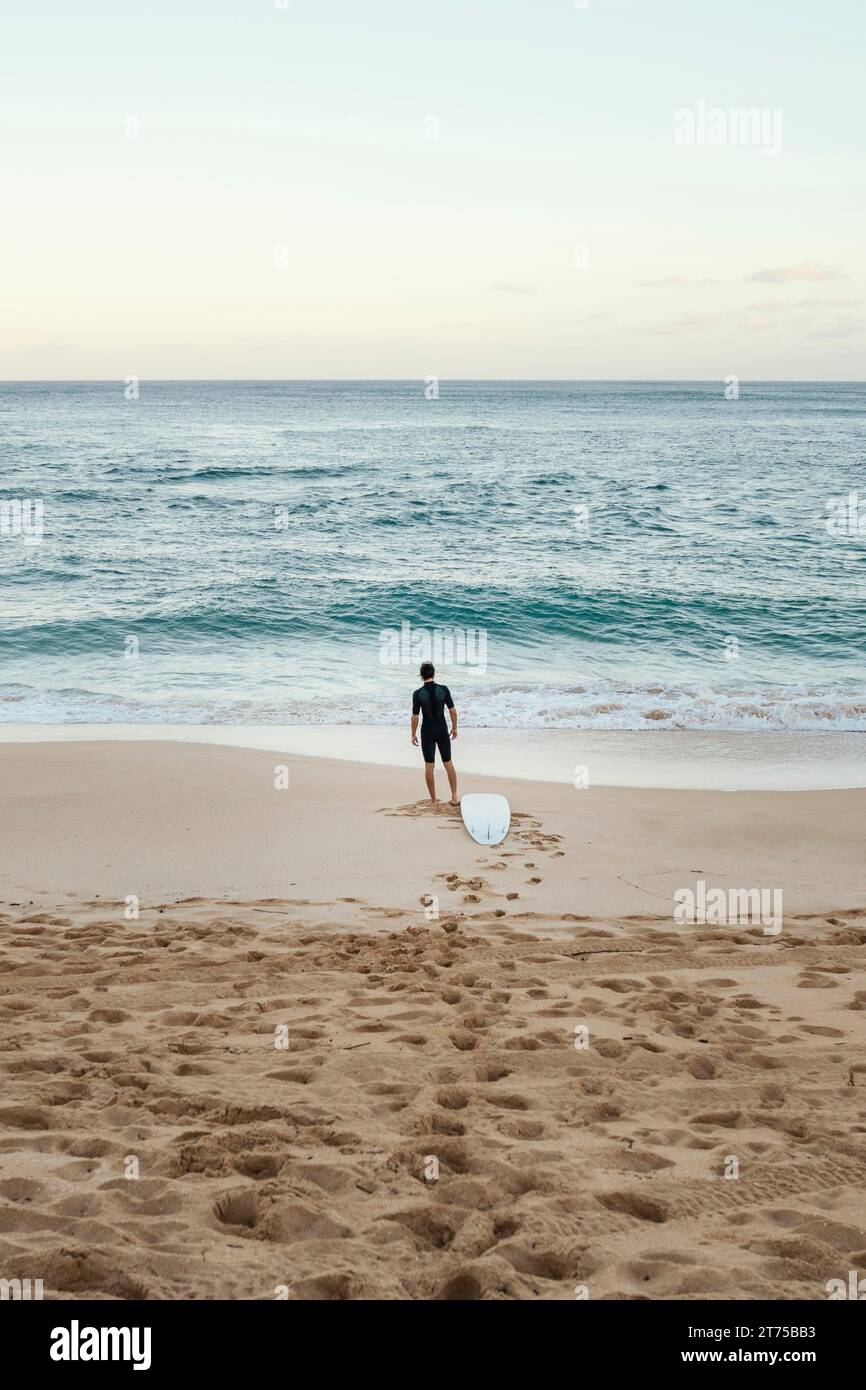 Surfer Mann, der auf dem Meer aussehend vertikal ist Stockfoto