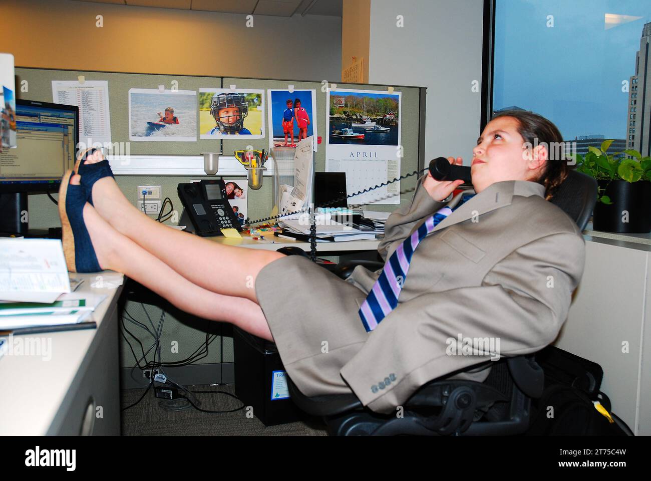 Ein junges Mädchen trägt Anzug und Krawatte und arbeitet während des Bring You Child to Work Day an den Telefonen in einem Büro Stockfoto