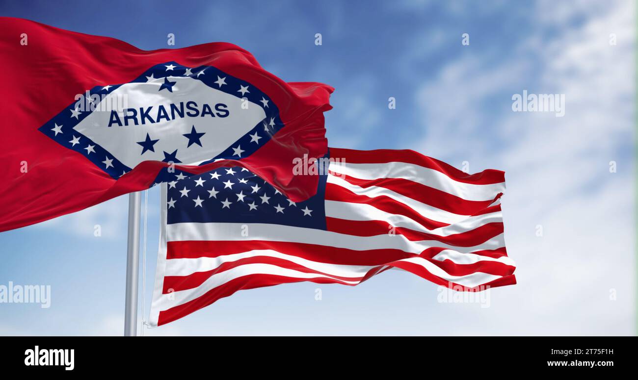 Arkansas- und US-amerikanische Flaggen winken zusammen und symbolisieren die staatliche und nationale Einheit vor einem wolkengefaßten blauen Himmel Stockfoto