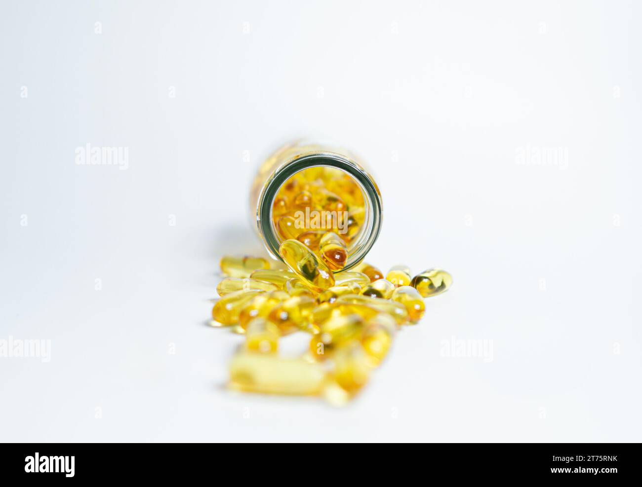 Fischöl Ergänzungskapseln für Gesundheit Spill out aus Klarglas Flasche mit goldener Kappe isoliert auf weißem Hintergrund Stockfoto