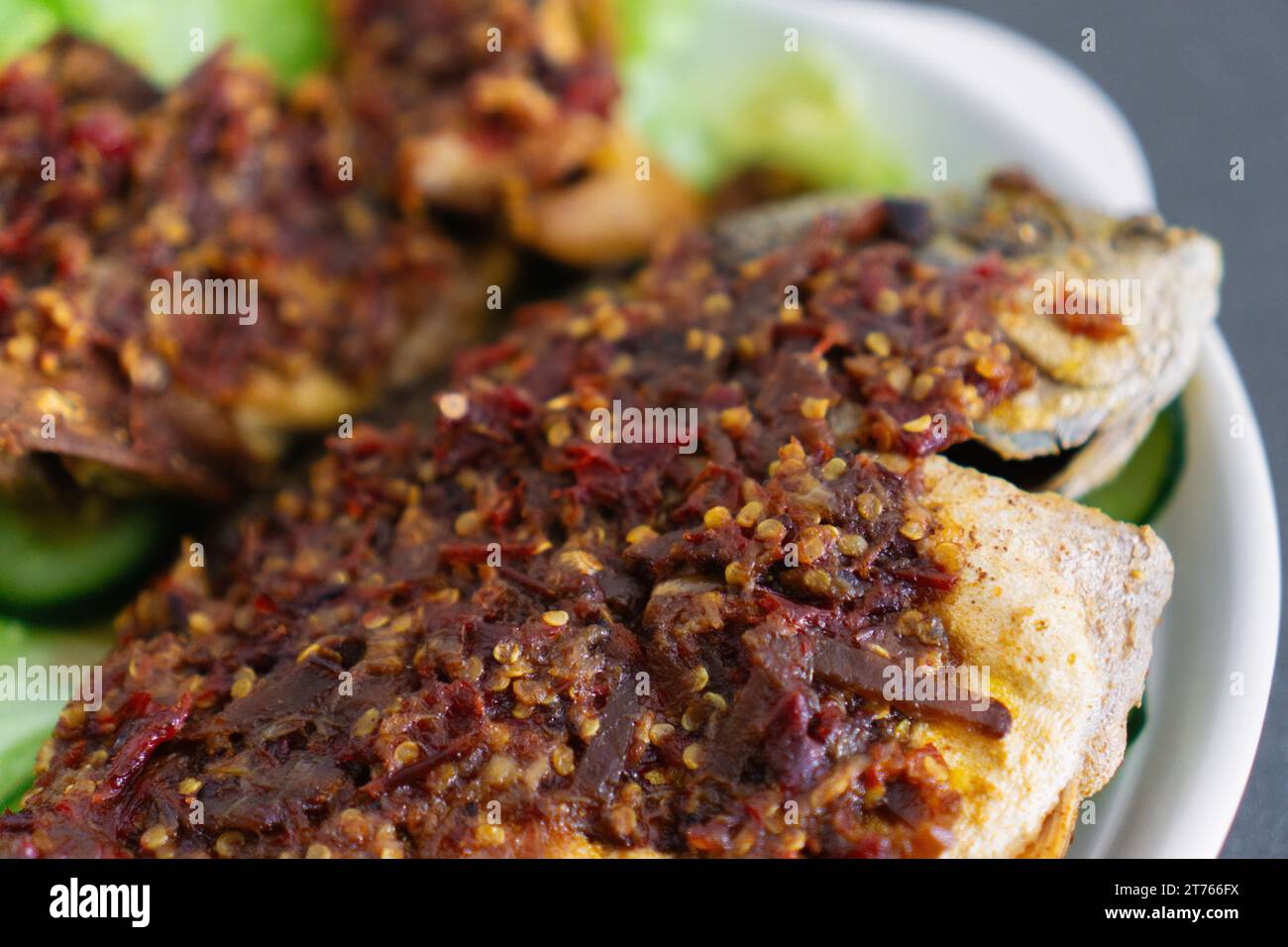 Ikan Goreng Masak Sambal, gebratener Fisch mit Chilipaste. Traditionelles indonesisches und malaysisches Gericht. Nahaufnahme Stockfoto