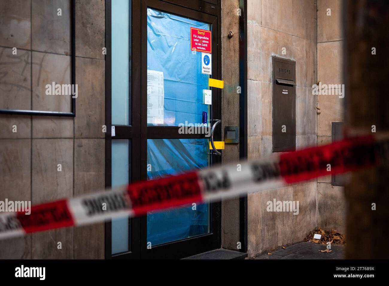 Hannover, Deutschland. November 2023. Barriereband fliegt nachts vor dem polizeiversiegelten Eingang zu einem Kasino. Ein Mann wurde mit einer stechenden Waffe in der Arkade tödlich verwundet. Kredit: Moritz Frankenberg/dpa/Alamy Live News Stockfoto