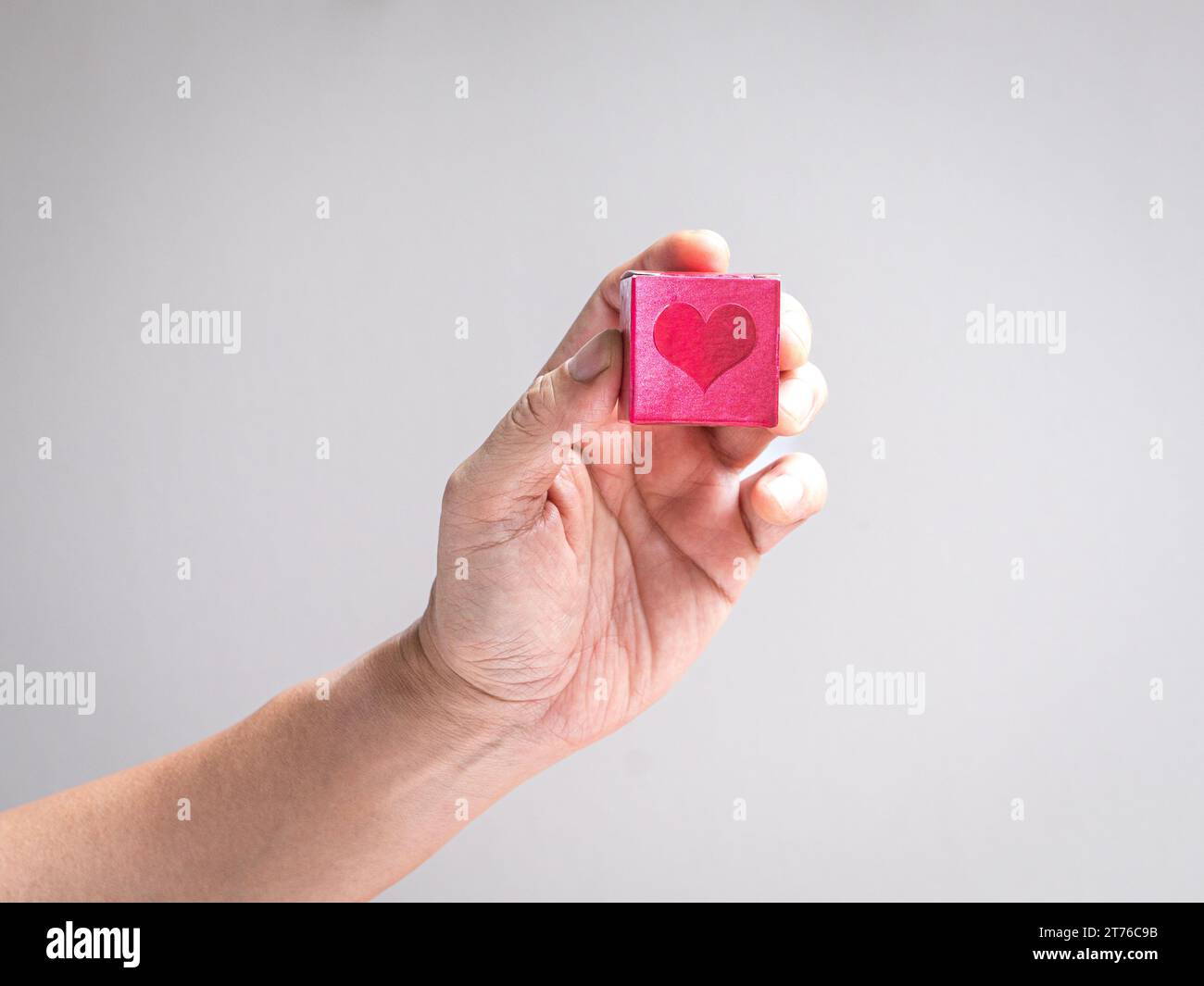 Die Hand hält eine rote Box mit Herzform. Wohltätigkeits-, Spenden- oder Liebeskonzept. Stockfoto