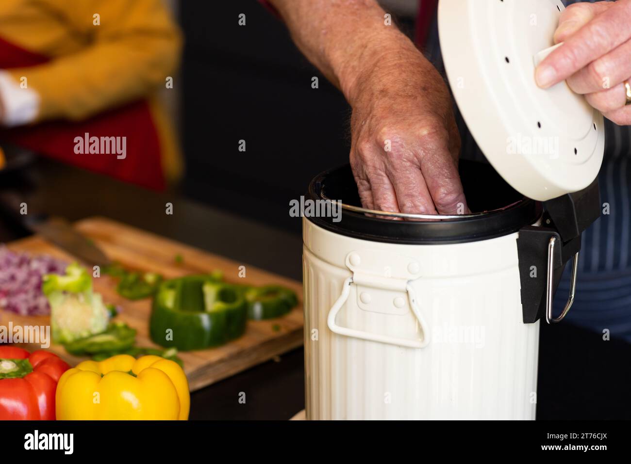 Der mittlere Teil des kaukasischen Seniors, der Essen zubereitete, Gemüseabfälle in der Küche kompostierte Stockfoto