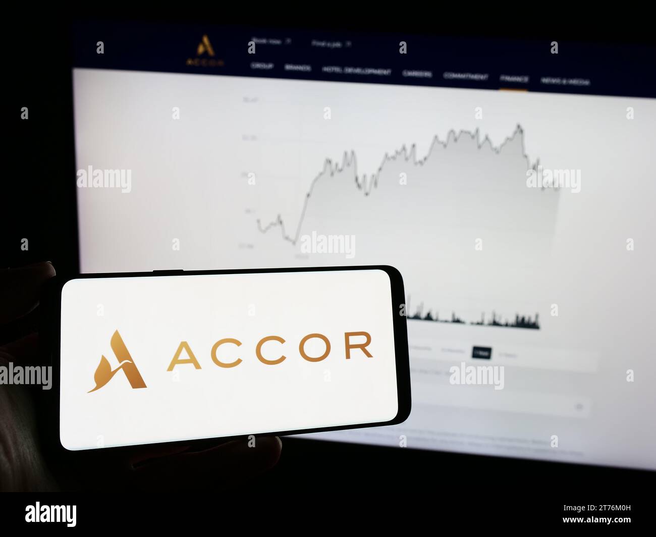 Person, die ein Mobiltelefon mit dem Logo des französischen Hotelunternehmens Accor SA vor der Business-Webseite hält. Schwerpunkt auf dem Display des Telefons. Stockfoto