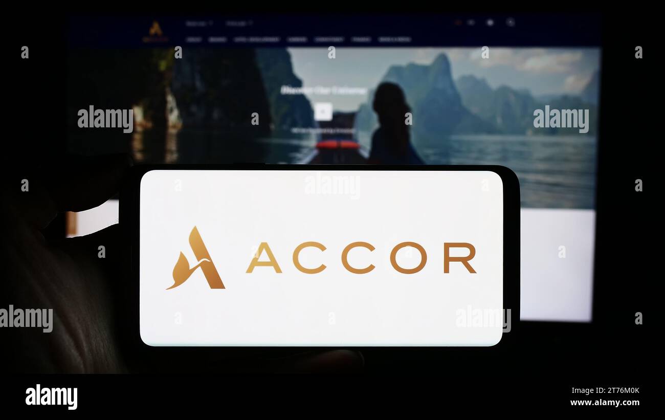 Person mit Smartphone und Logo des französischen Hotelunternehmens Accor S.A. vor der Website. Schwerpunkt auf dem Display des Telefons. Stockfoto