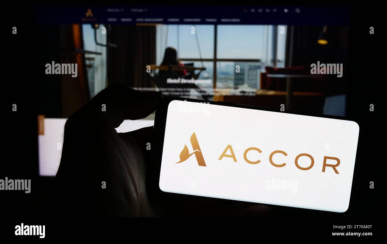 Person, die ein Mobiltelefon mit dem Logo des französischen Hotelunternehmens Accor S.A. vor der Webseite hält. Schwerpunkt auf dem Display des Telefons. Stockfoto
