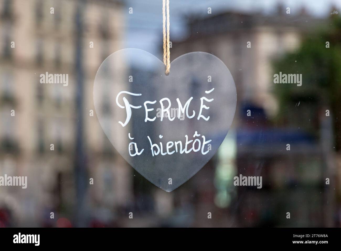 Nahaufnahme eines herzförmigen Schildes mit der Aufschrift „Fermé, à bientôt“, was auf Englisch „geschlossen, bis bald“ bedeutet. Stockfoto