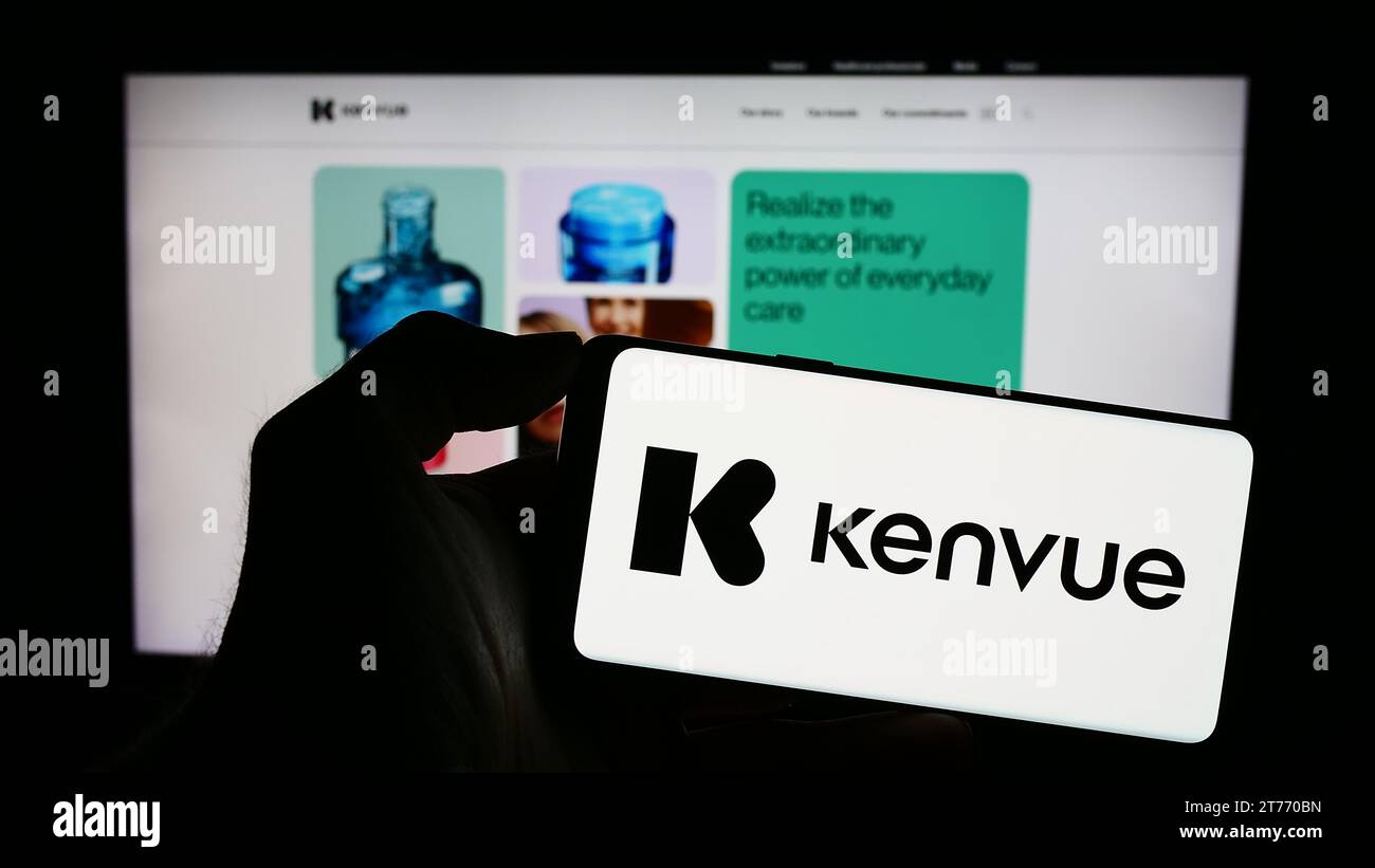 Person, die ein Mobiltelefon mit dem Logo des amerikanischen Unternehmens für Gesundheitsprodukte Kenvue Inc. Vor der Webseite hält. Schwerpunkt auf dem Display des Telefons. Stockfoto