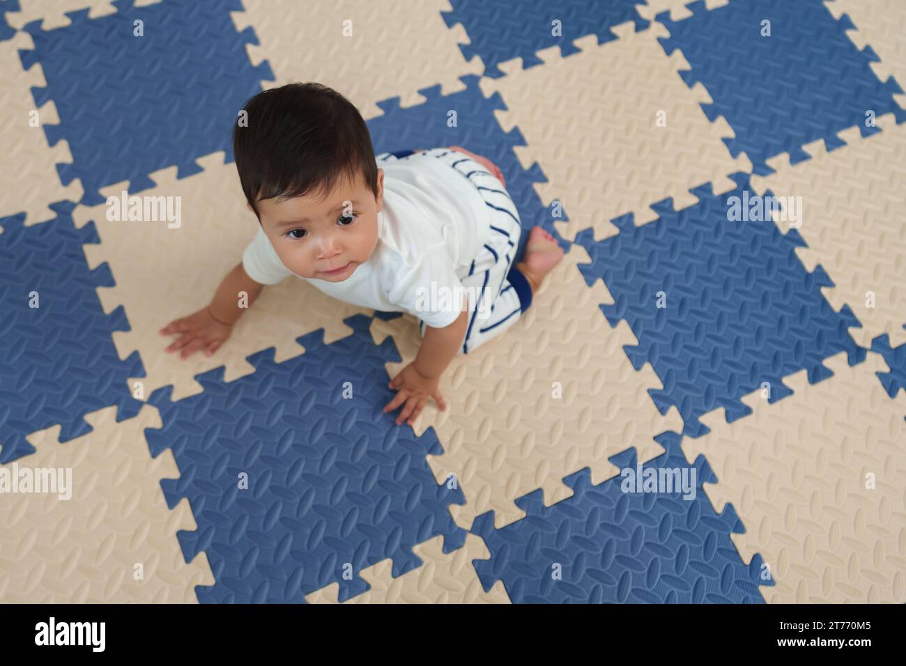 Draufsicht des Babys, das auf der Spielmatte oder dem Puzzle-Boden krabbelt Stockfoto