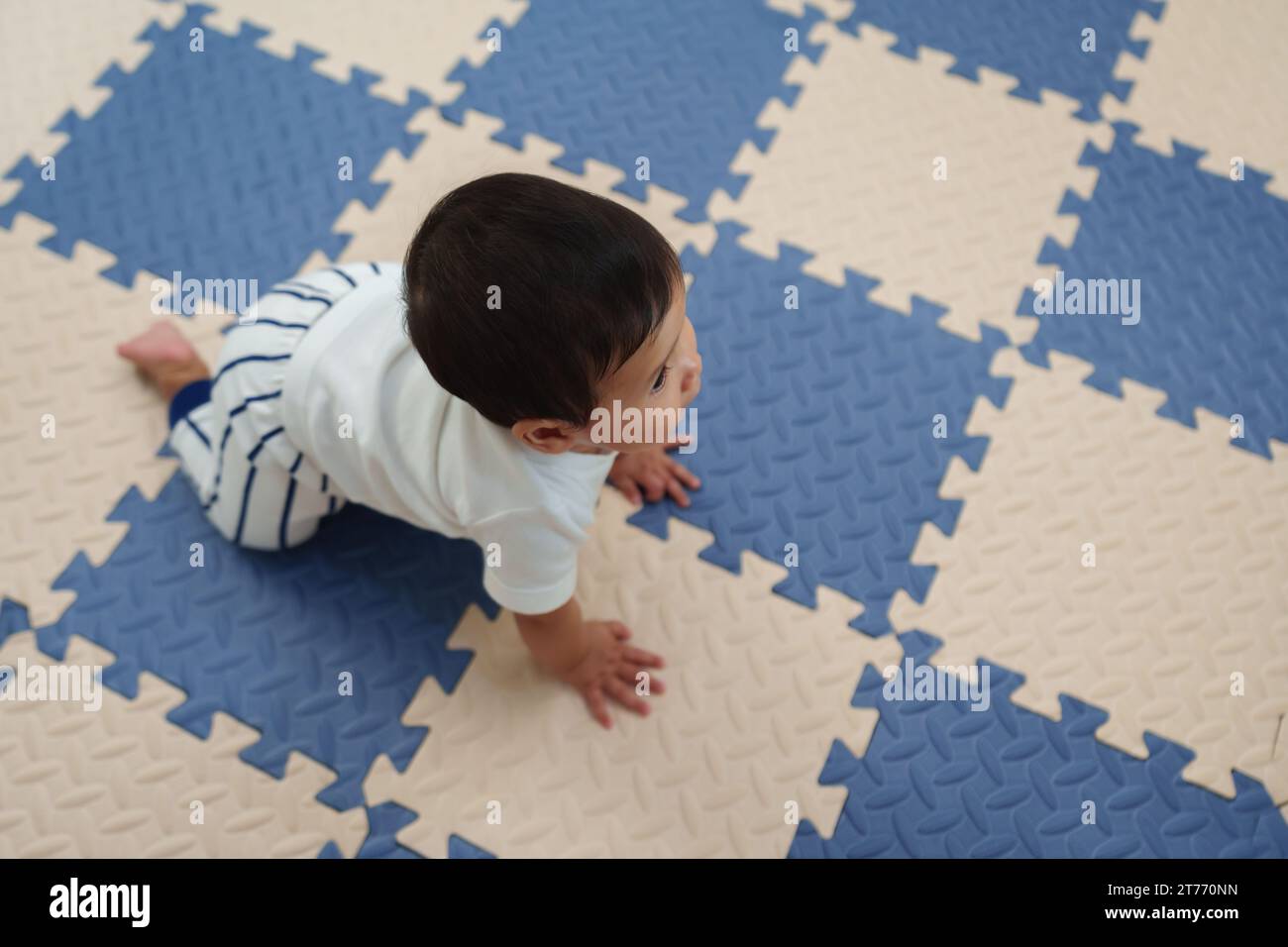Draufsicht des Babys, das auf der Spielmatte oder dem Puzzle-Boden krabbelt Stockfoto