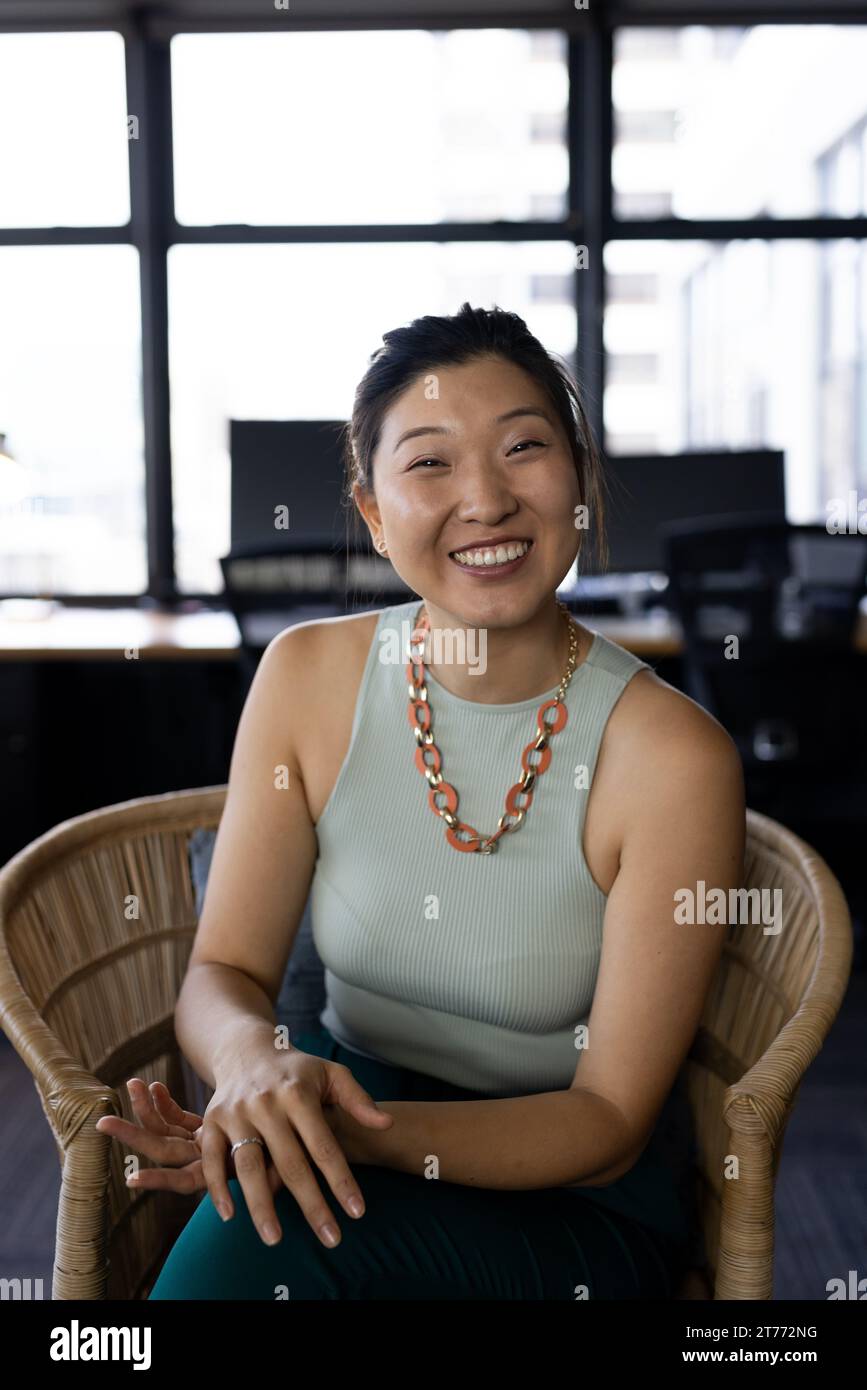 Glückliche asiatische Geschäftsfrau mit Videoanruf, lächelnd im Sessel im Büro, Kopierraum Stockfoto