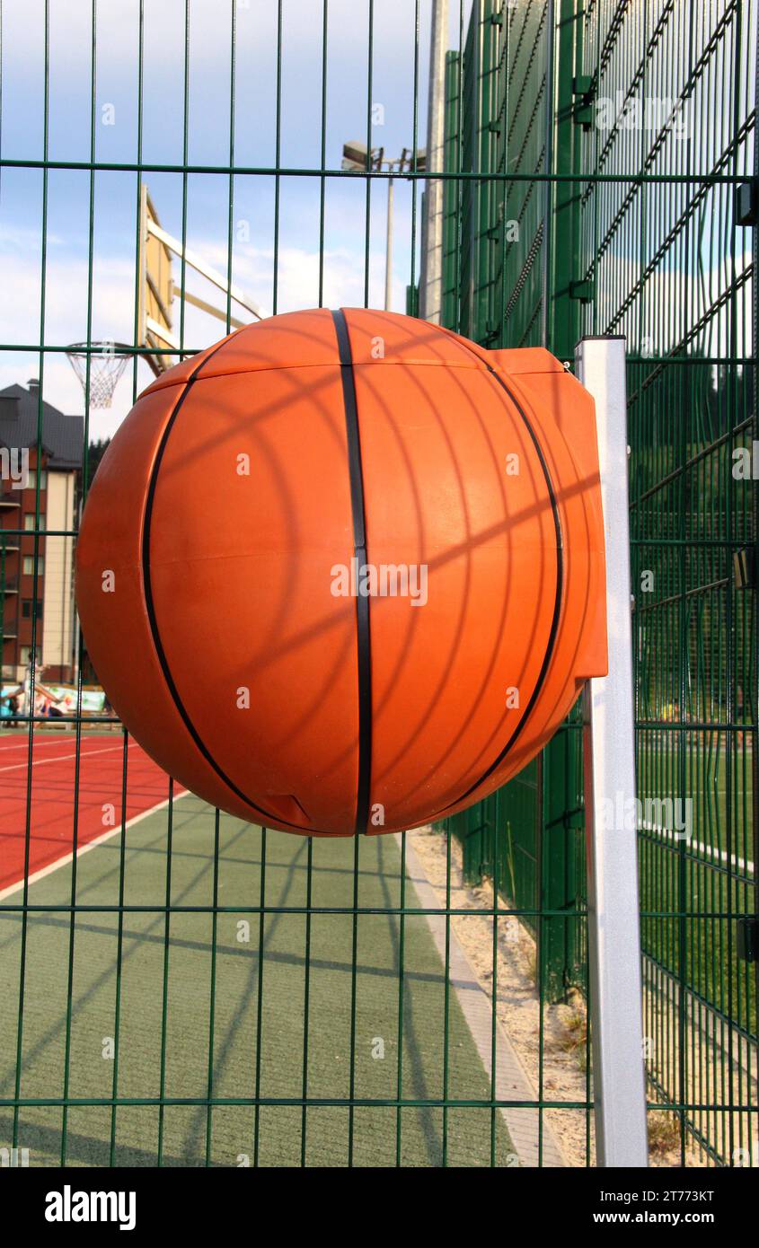 Plastikmülldose in Form eines Basketballballs auf einem Sportplatz Stockfoto