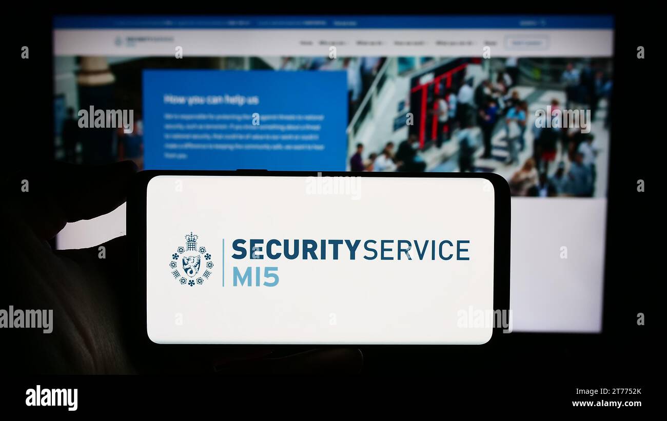Person, die ein Smartphone mit dem Logo der britischen Geheimdienstabwehr Security Service (MI5) vor der Website hält. Schwerpunkt auf dem Display des Telefons. Stockfoto