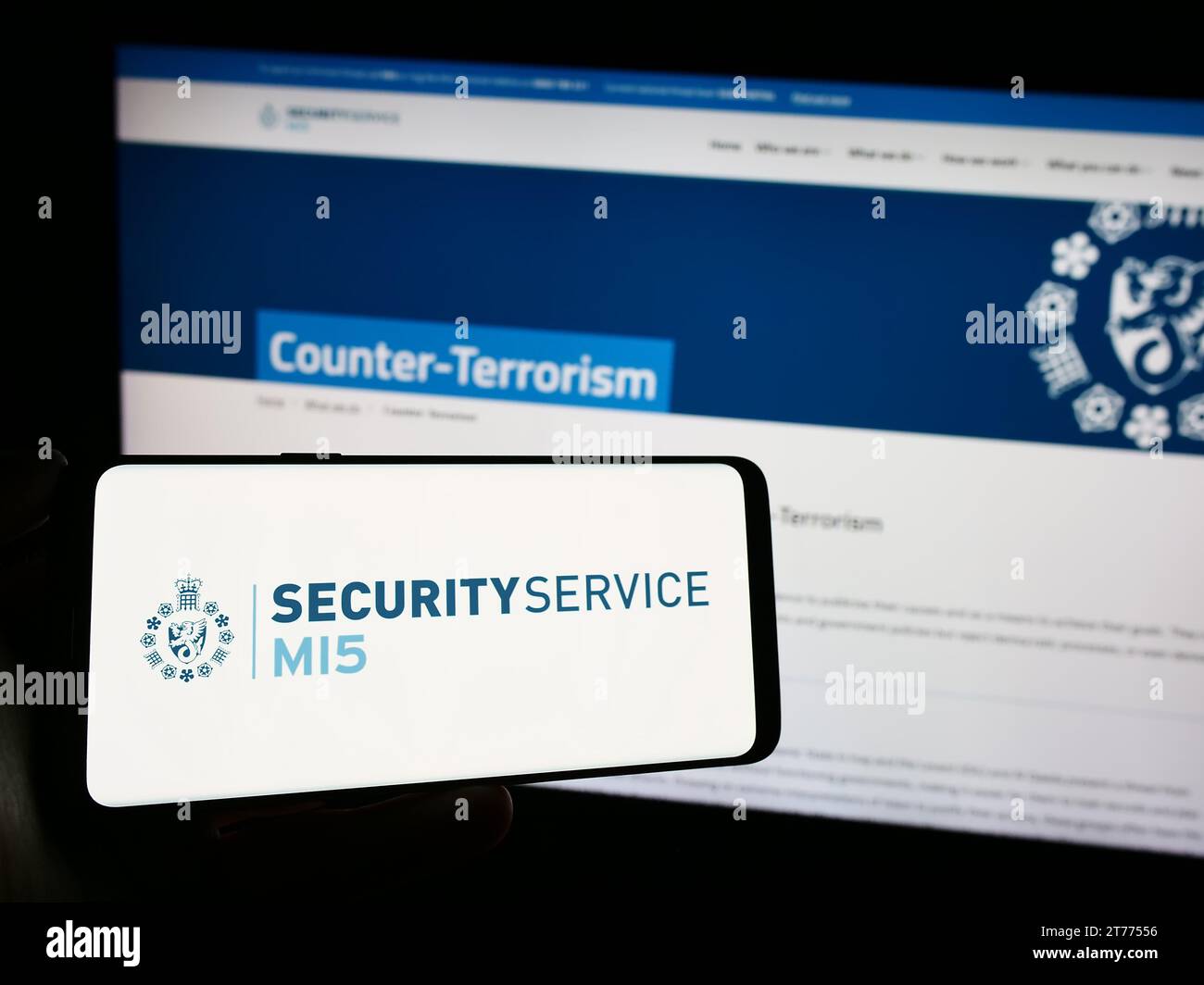 Person, die ein Handy hält, mit dem Logo des britischen Geheimdienstes Security Service (MI5) vor der Webseite. Schwerpunkt auf dem Display des Telefons. Stockfoto