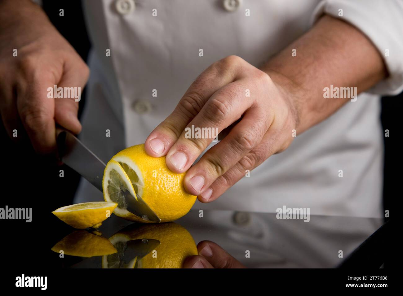 Nahaufnahme einer Koch-Hände schneiden eine Zitrone Stockfoto