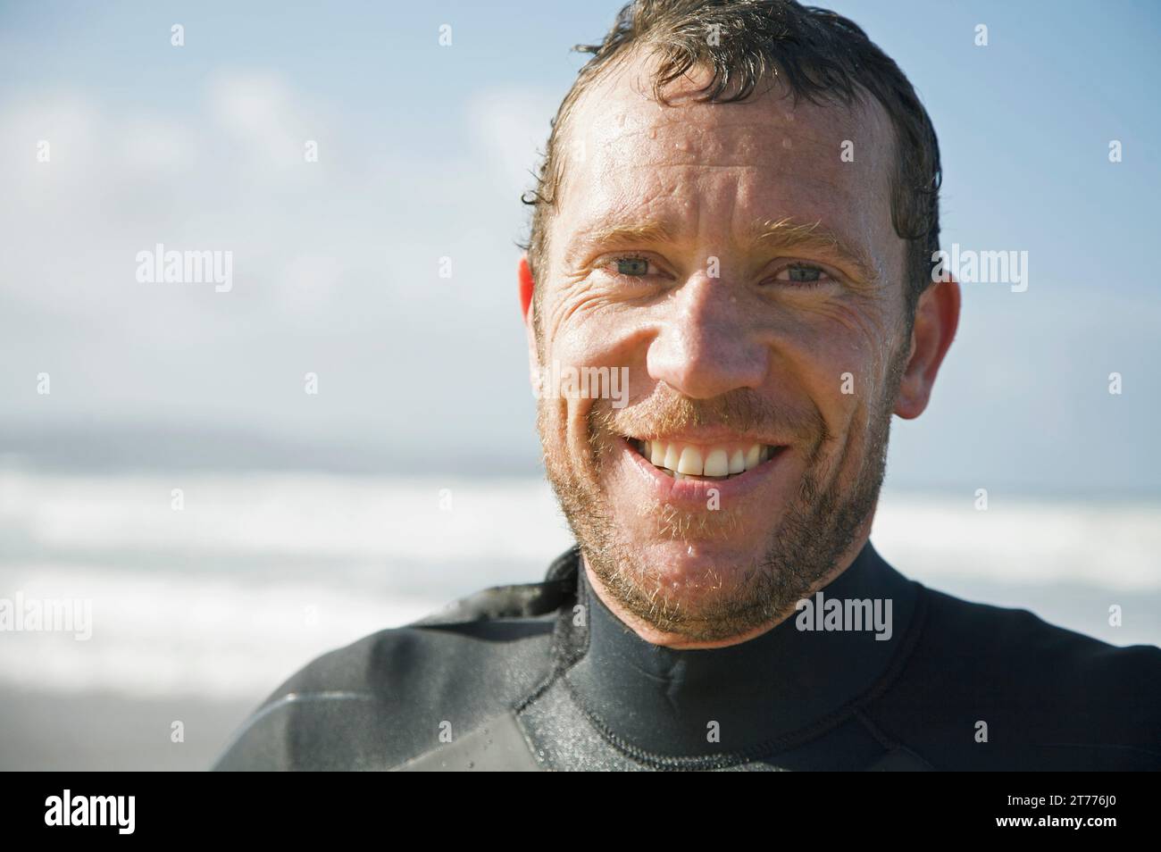 Lächelnder Surfer am Strand Stockfoto