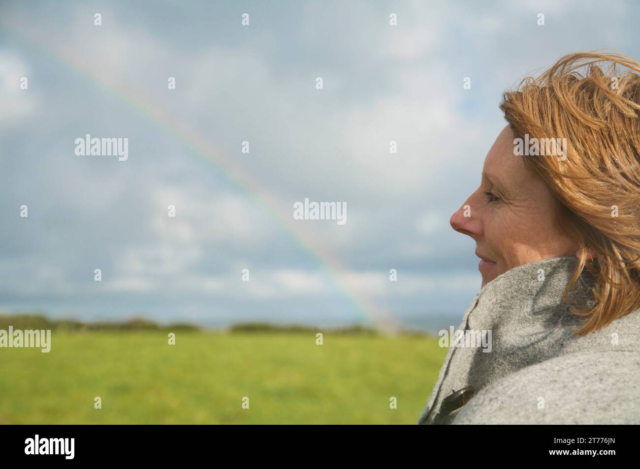 Nahaufnahme von einer Frau, in einem Feld, Blick auf den Regenbogen Stockfoto