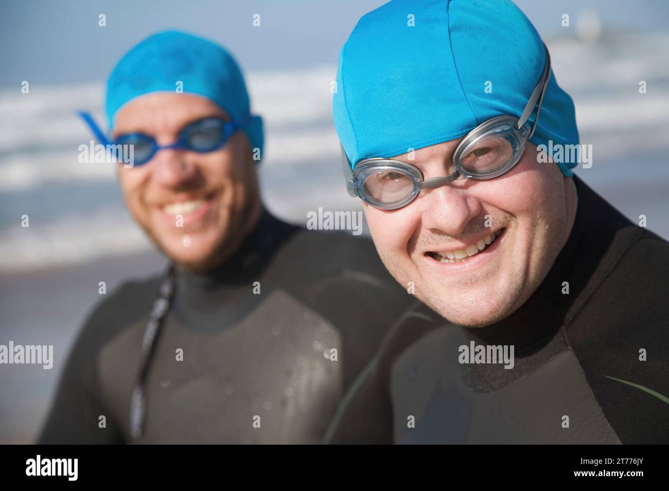Zwei Männer tragen Badekappen und Schwimmbrillen lächelnd Stockfoto