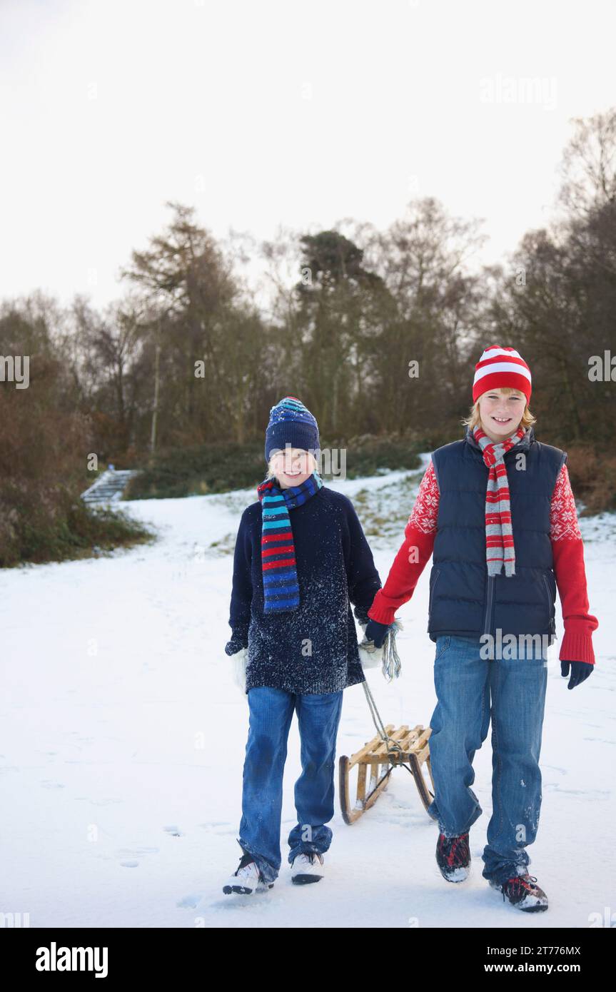 Porträt von zwei jungen Wandern im Schnee, einen Schlitten ziehen Stockfoto