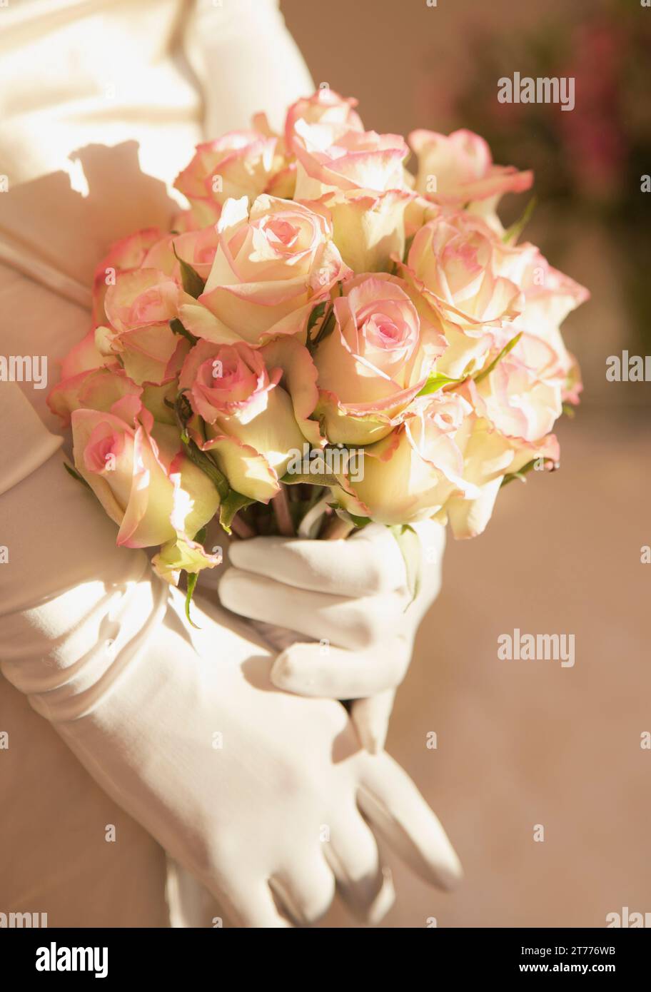 Nahaufnahme von einer Braut behandschuhten Hände halten einen Strauß Rosen Stockfoto