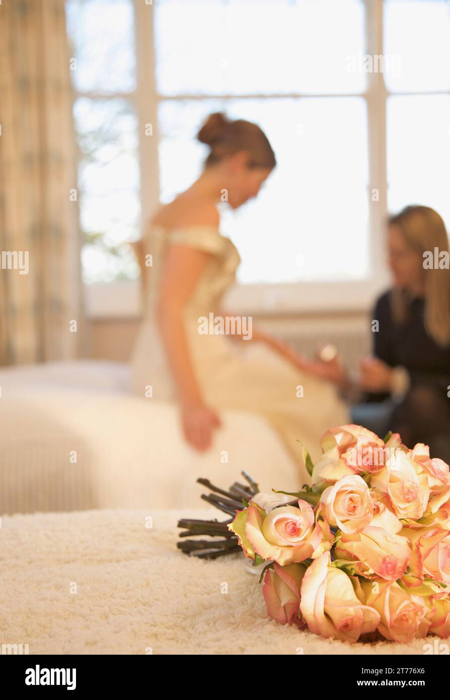 Nahaufnahme von einem Strauß Rosen auf einem Bett liegend mit Braut empfangen eine Maniküre Stockfoto