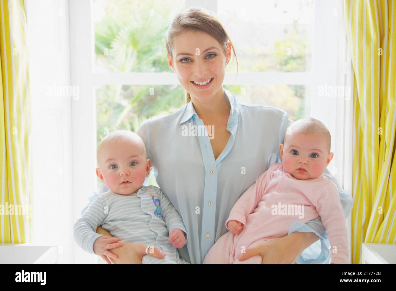 Lächelnde Mutter Holding Zwillingen Stockfoto