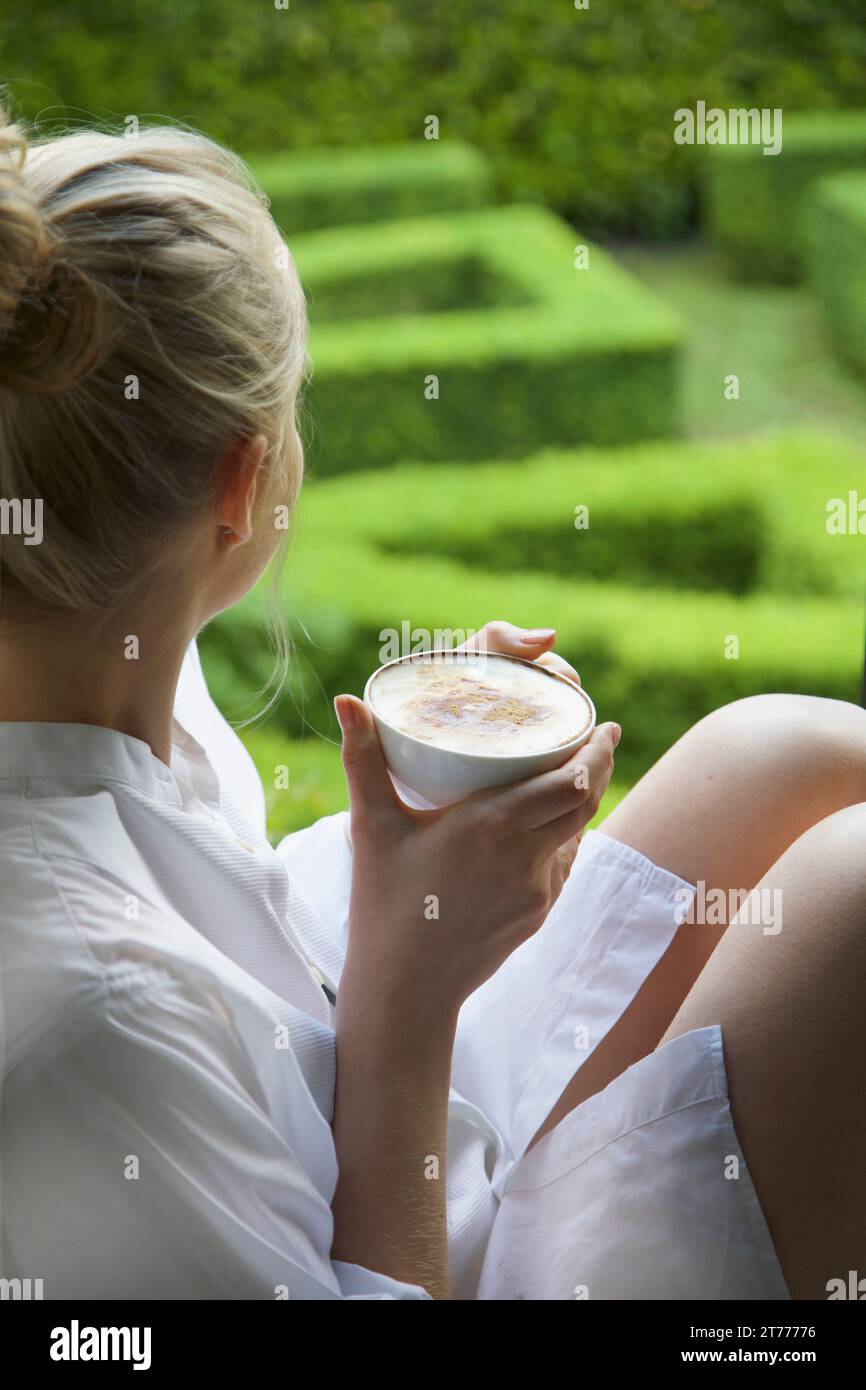 Frau mit Cappuccino sah Out in Garten Stockfoto