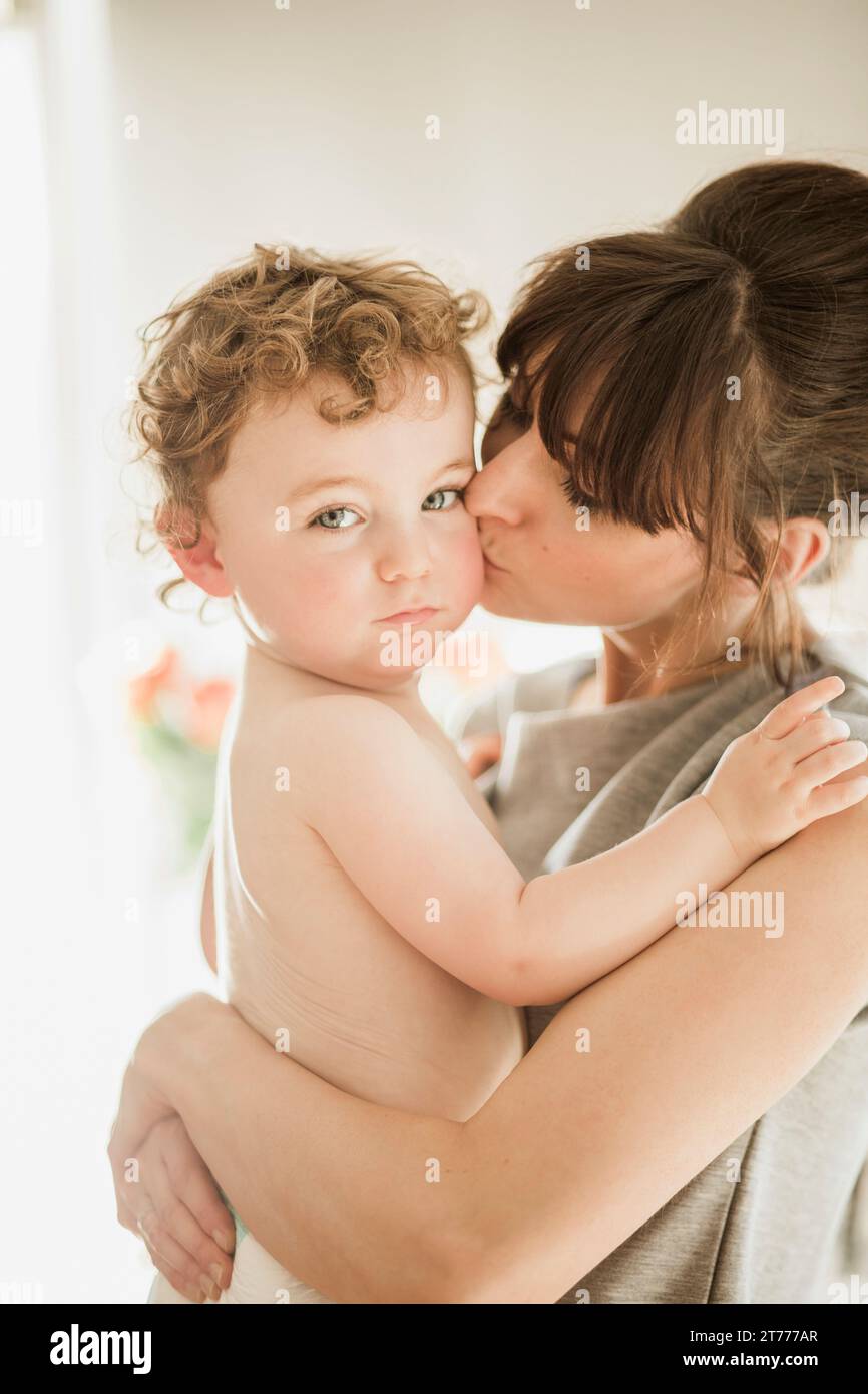 Halten und küssen Baby Sohn Mutter Stockfoto