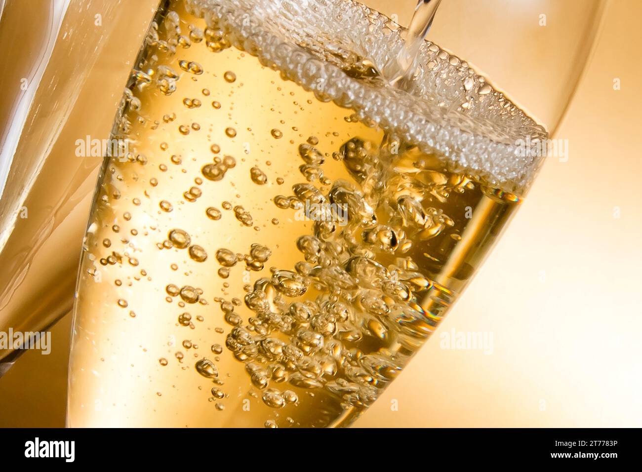 Leere Gläser Champagner und eines vor goldenem Hintergrund gefüllt Stockfoto