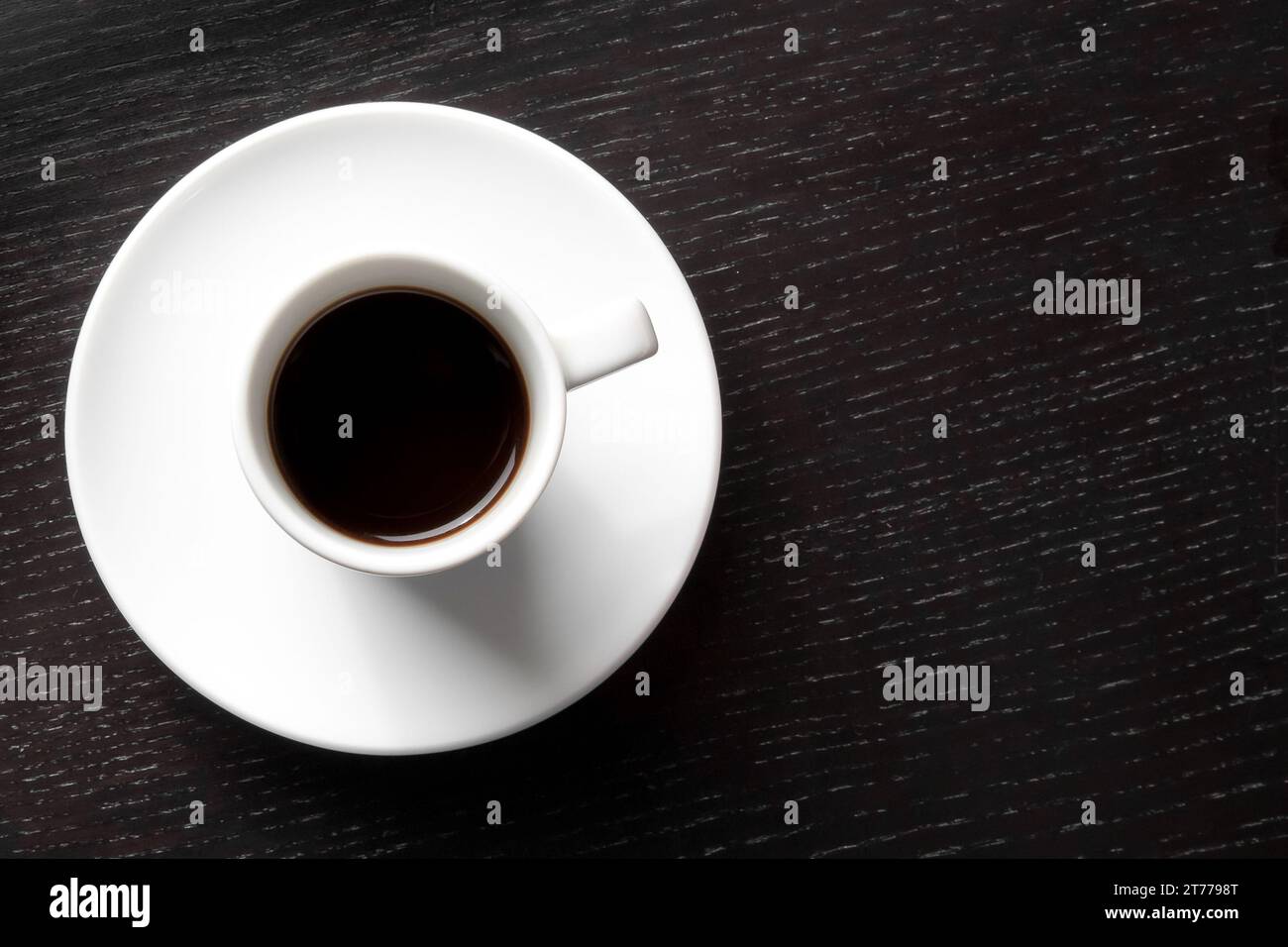 Ansicht von oben auf eine weiße Tasse mit Kaffee mit Platz für Text über schwarzem Holztisch Stockfoto