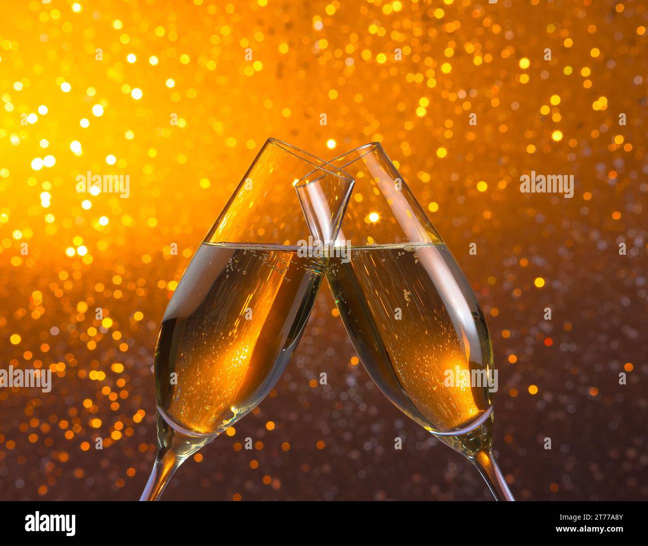 Champagnerflöten jubeln auf goldenem, hellem Bokeh-Hintergrund Stockfoto