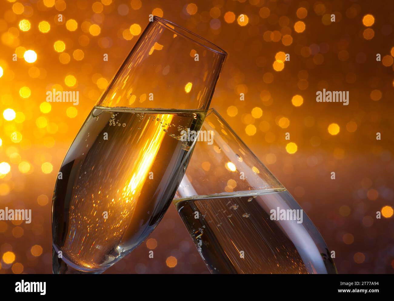 Zwei Sektflöten mit goldenen Luftblasen geben Anfeuerungen auf dunklem, hellem Bokeh-Hintergrund Stockfoto