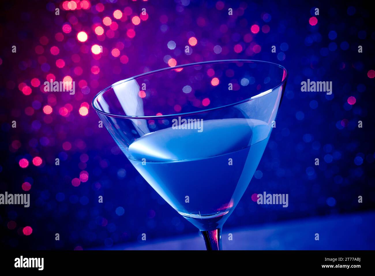Glas-blauer Cocktail auf blauem und violettem Hintergrund auf dem Tisch Stockfoto